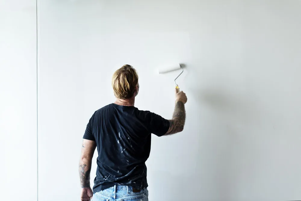 Maler streicht eine Wand mit der Rolle weiß